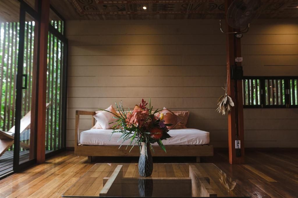 Sitzbereich im Zimmer mit Holzsofa, Holzwänden und einem Blumenstrauß auf dem Tisch.