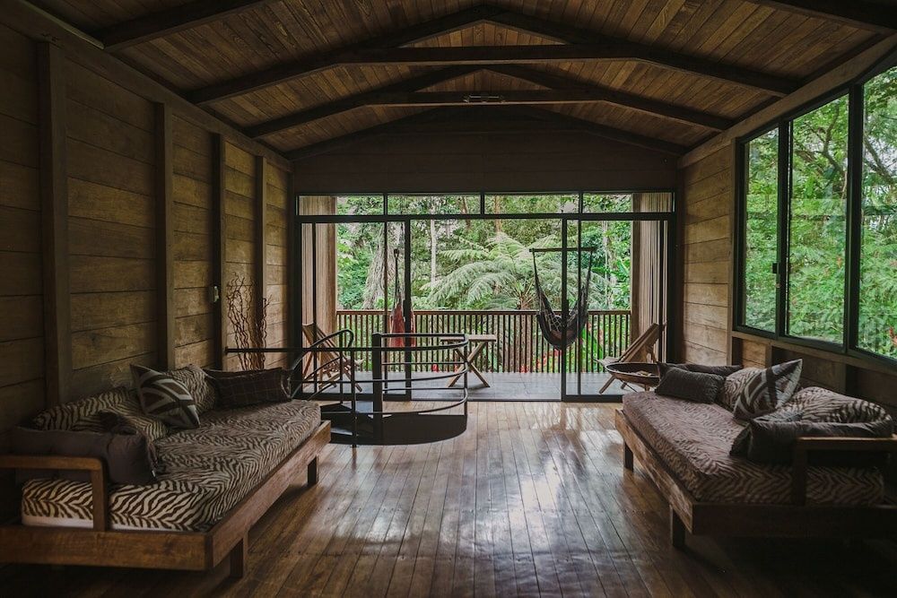 Geräumiger Innenraum aus Holz mit Sitzbänken und Übergang zur schattigen Terrasse.