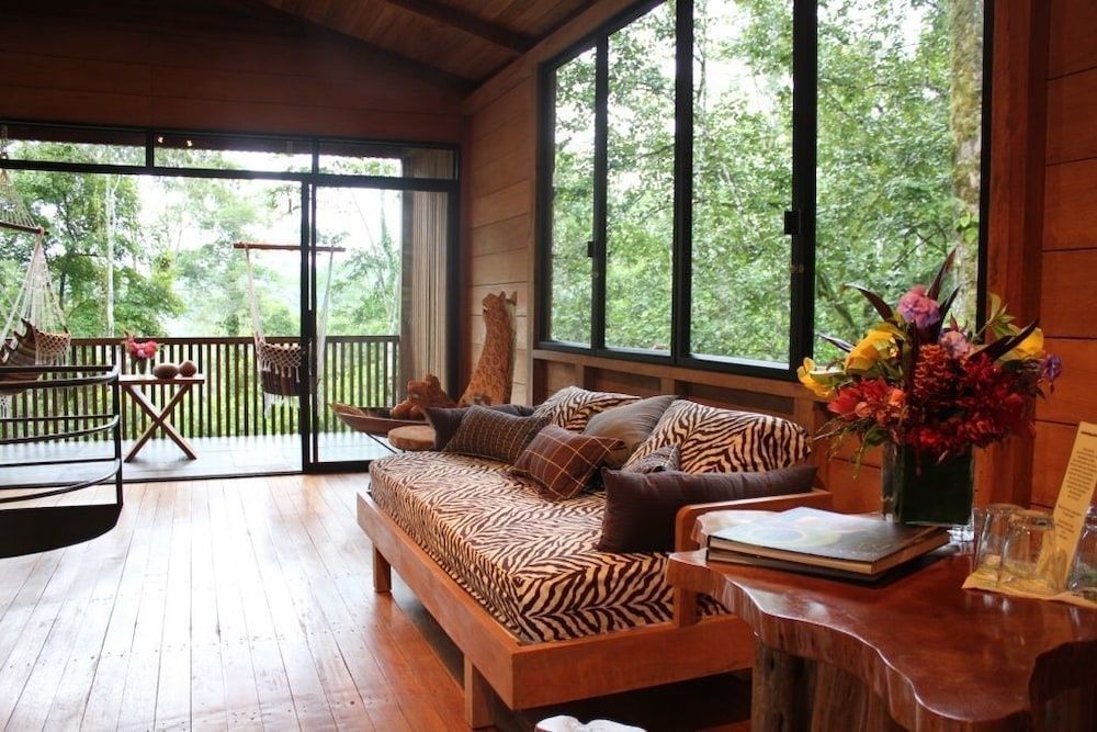 Sitzbereich mit zebragemustertem Sofa und großen Fenstern zum grünen Außenbereich.
