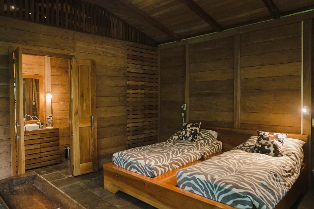 Schlafzimmer aus Holz mit zwei Einzelbetten und gemusterten Tagesdecken.
