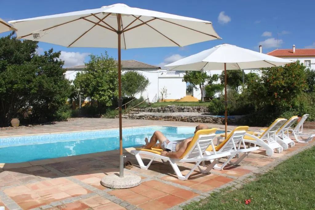 Außenpool mit zwei Sonnenschirmen und Liegestühlen auf der Terrasse.