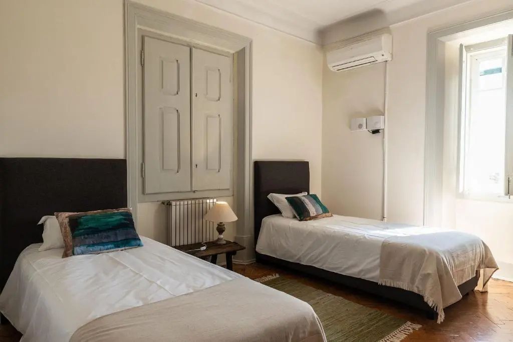 Schlafzimmer mit zwei Einzelbetten, weißer Bettwäsche und Holzfensterläden.