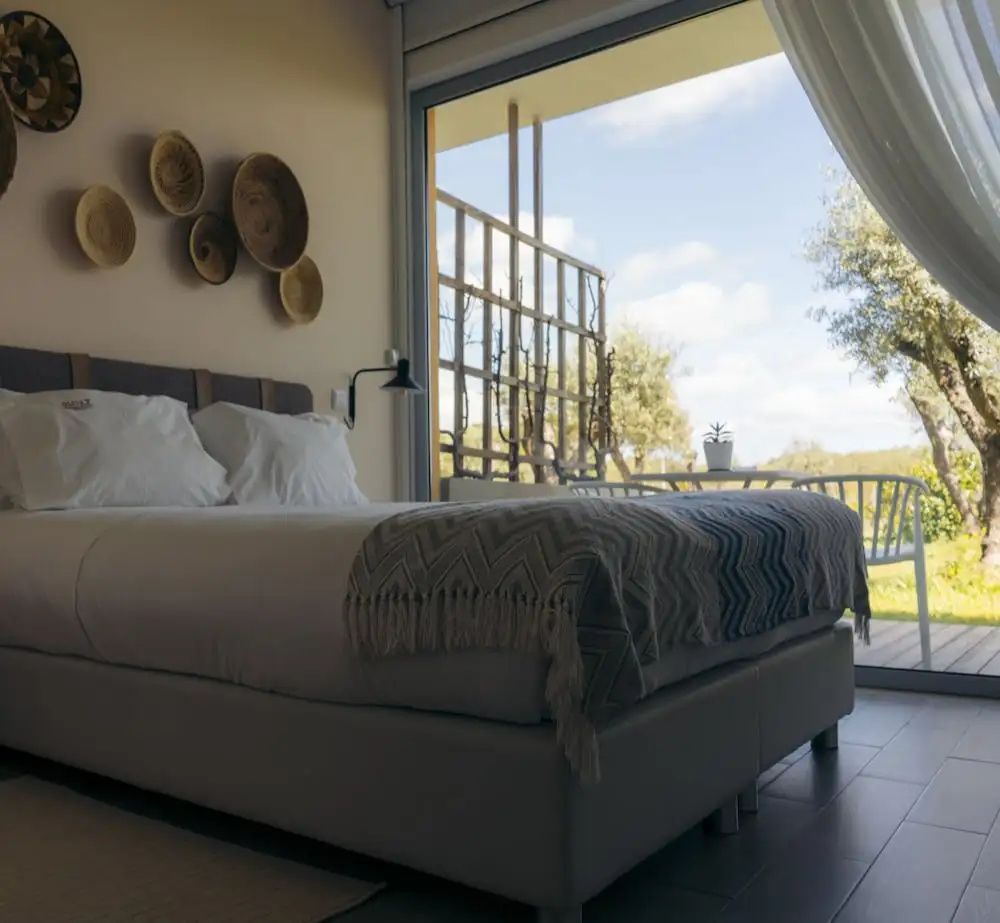 Modernes Zimmer mit Doppelbett, Korbdekoration an der Wand und Blick auf den Garten.
