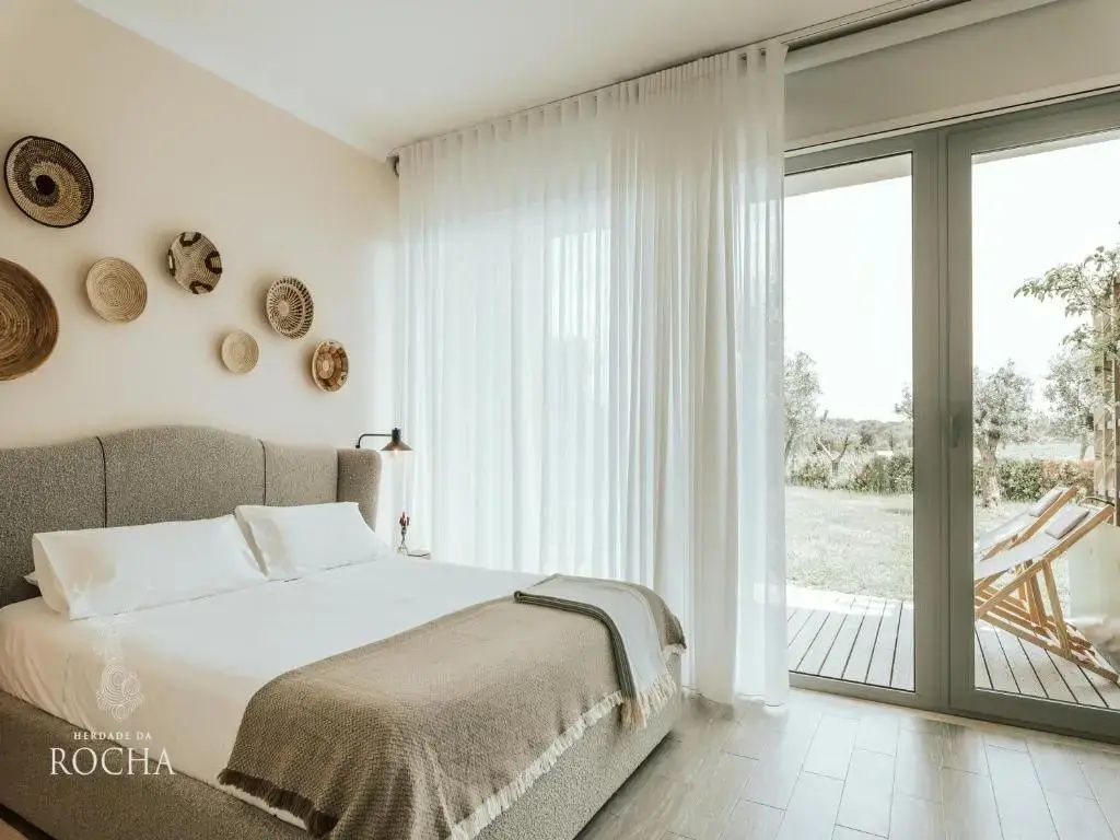 Modernes Schlafzimmer mit Doppelbett und Blick ins Grüne durch die Terrassentür.