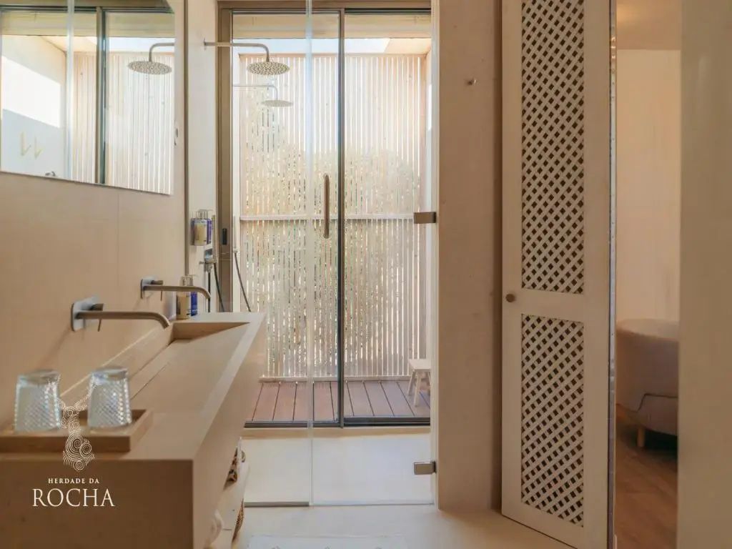Badezimmer mit modernem Waschtisch und einer bodengleichen Glasdusche.