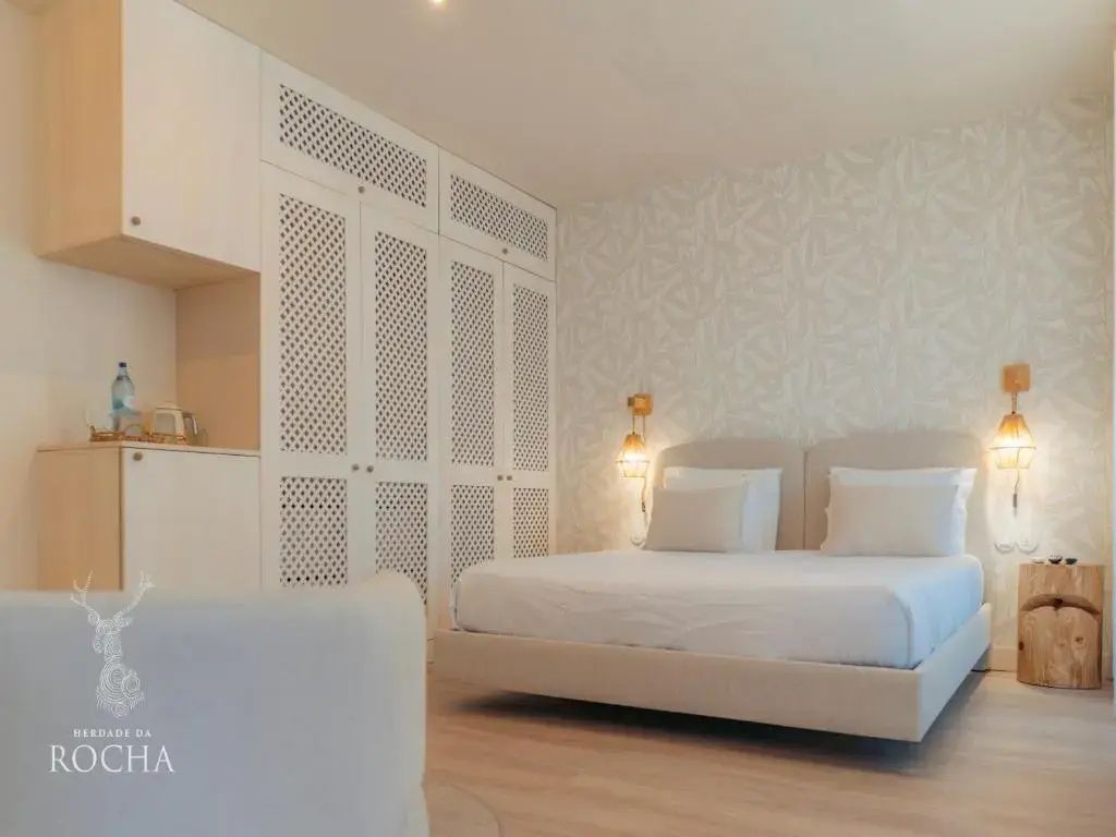 Helles Hotelzimmer mit Doppelbett, weißem Schrank mit Muster und Parkettboden