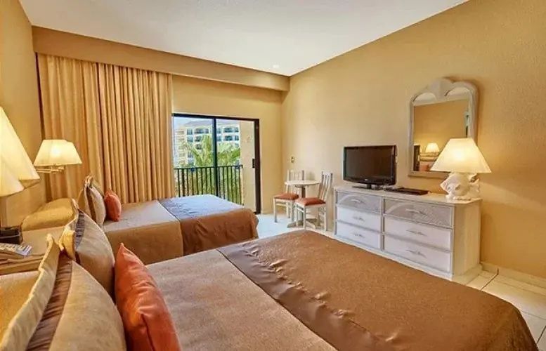 Schlafbereich im Hotelzimmer mit zwei Betten, Kommode, TV und Balkonaussicht.
