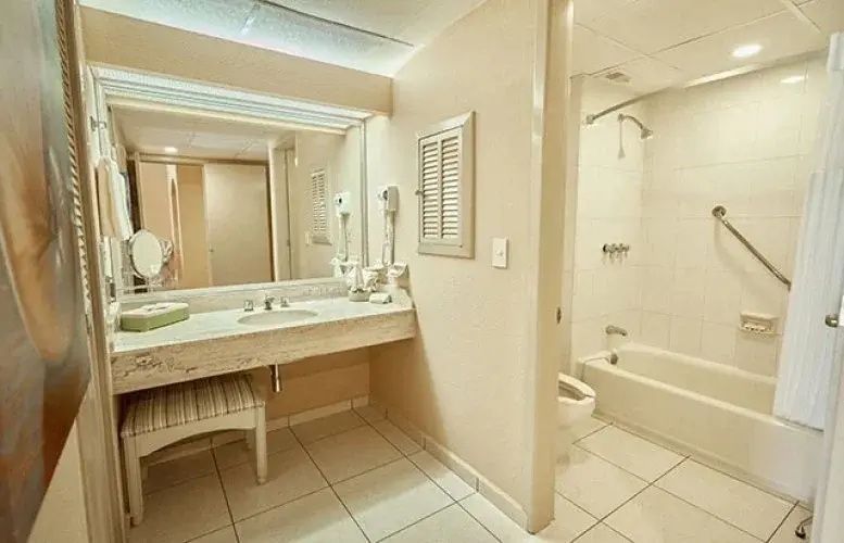 Badezimmer mit großem Spiegel am Waschtisch sowie Badewanne und Duschvorrichtung.
