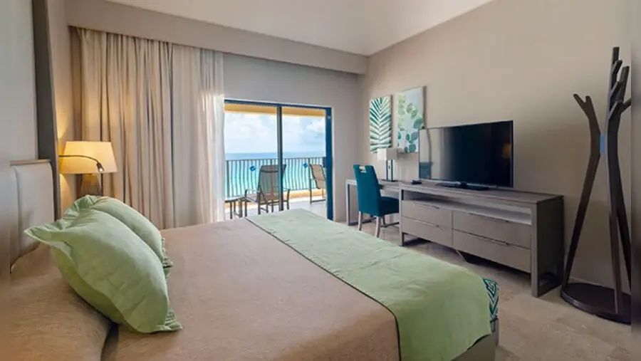 Hotelzimmer mit großem Doppelbett, Fernseher, Schreibplatz und Balkon zum Meer.