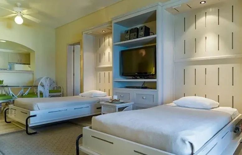 Zwei Einzelbetten in einem hell eingerichteten Hotelzimmer mit Fernsehelement.