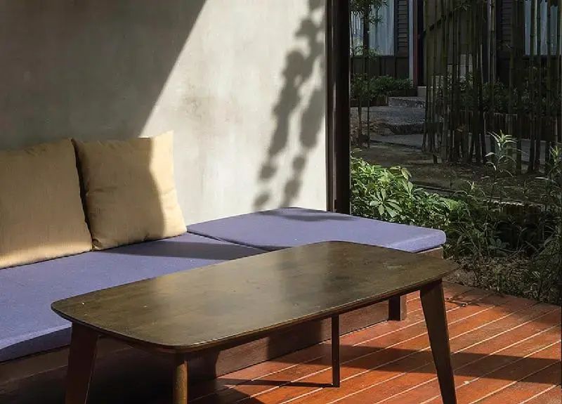 Nahaufnahme des Sitzbereichs auf der Terrasse mit blauen Polsterauflagen und Holztisch.