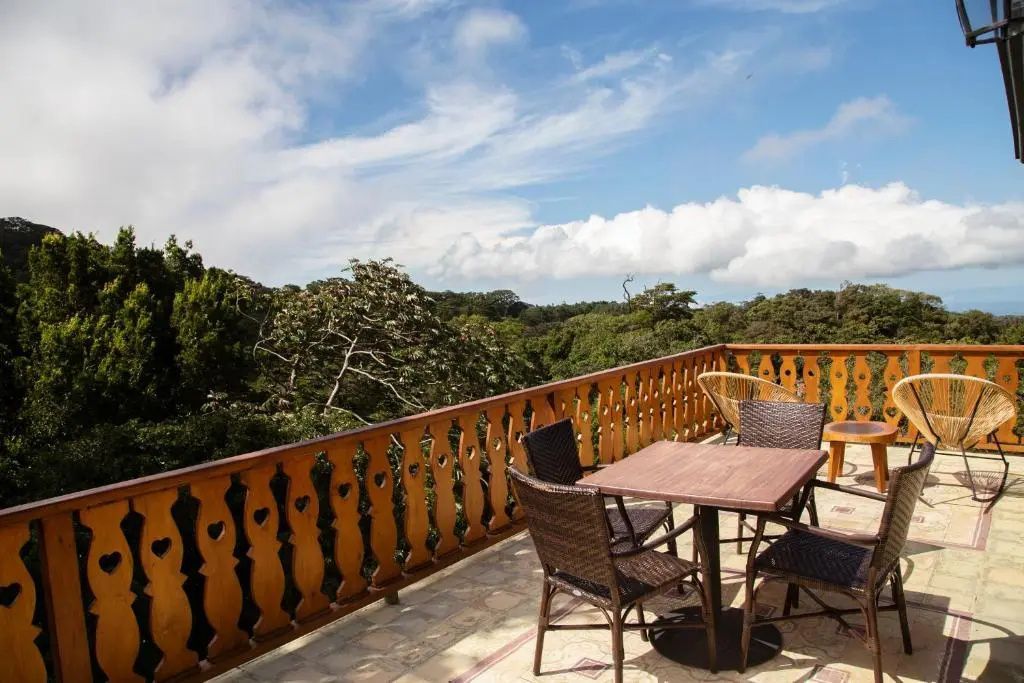 Terrasse mit Holzgeländer und Sitzgelegenheiten mit Ausblick auf den umliegenden Wald.