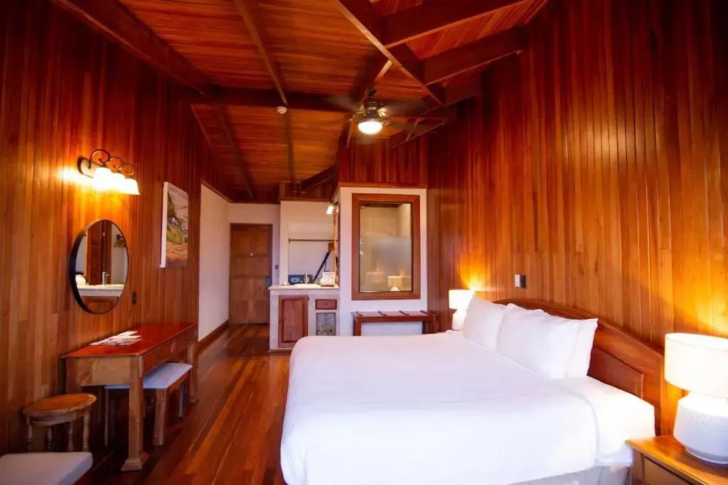 Schlafzimmer mit Holzverkleidung, großem Doppelbett und Deckenventilator.