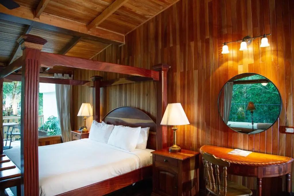 Schlafbereich mit hölzernem Himmelbett, Wandverkleidung aus Holz und Schminktisch.