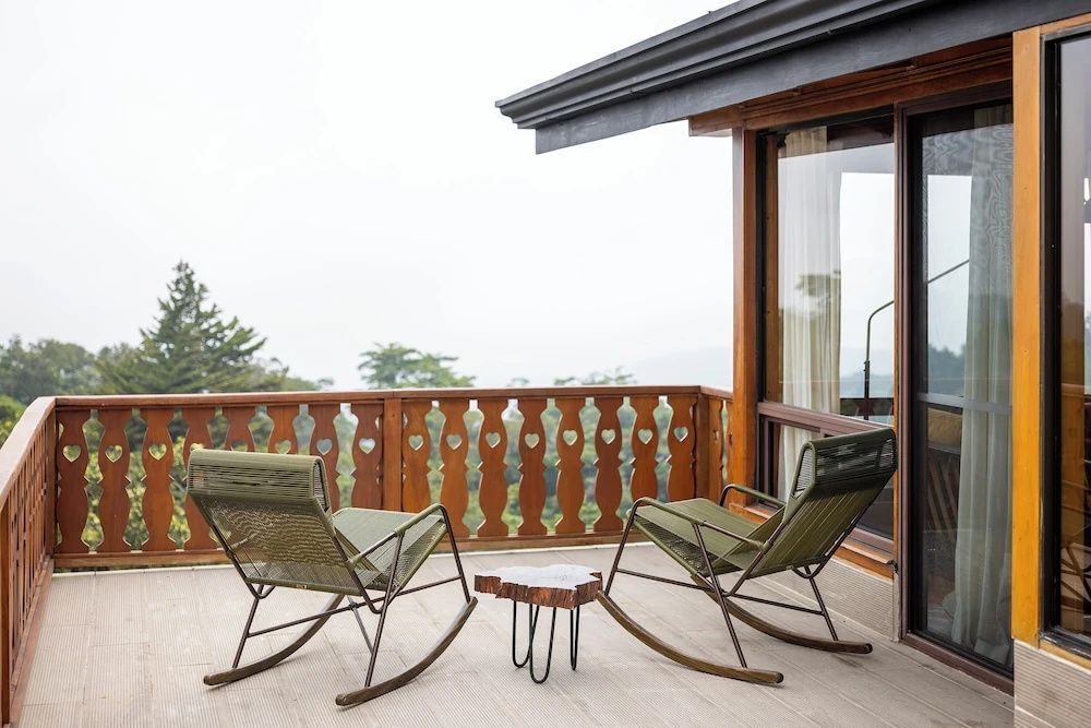 Zwei grüne Schaukelstühle aus Holz und ein kleiner Beistelltisch auf dem Balkon