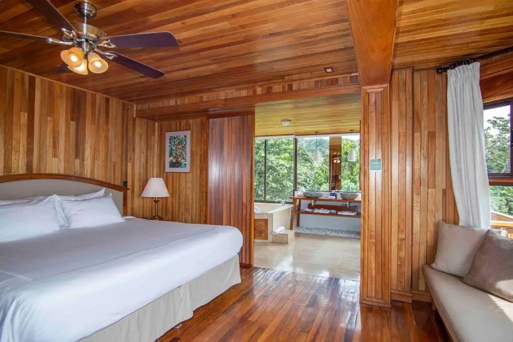Hotelzimmer aus Holz mit direktem Übergang zum offenen Badezimmer mit Badewanne.