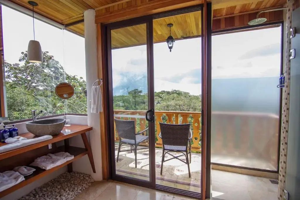 Schiebetür zum Balkon mit zwei Stühlen und Ausblick auf begrünte Hügel.
