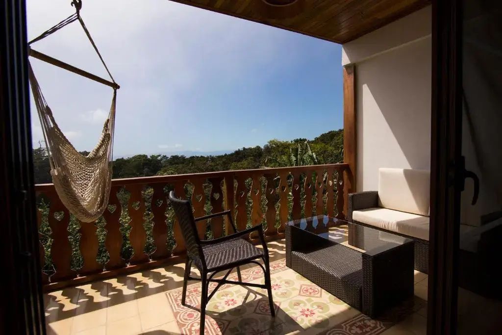 Überdachter Holzbalkon mit Sitzmöbeln, Hängematte und Ausblick auf den umgebenden Wald.