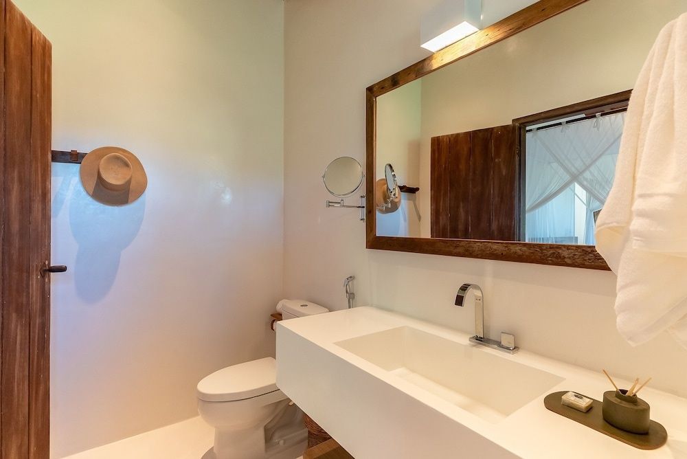 Modernes Badezimmer mit weißem Waschtisch, großem Holzspiegel und Toilette.
