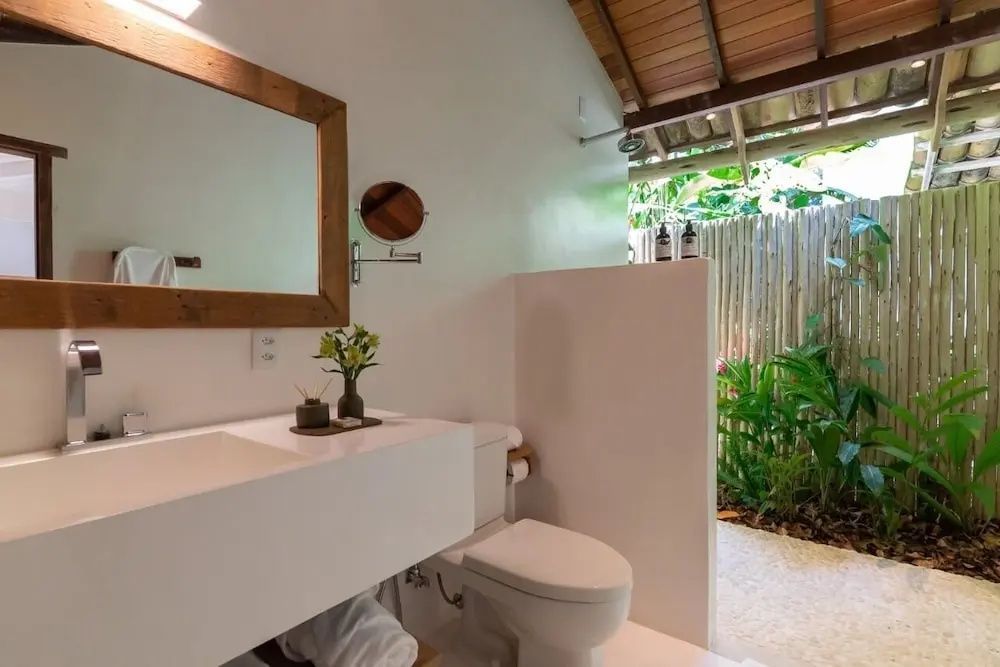 Badezimmer mit weißem Waschtisch, Toilette und Blick ins Grüne