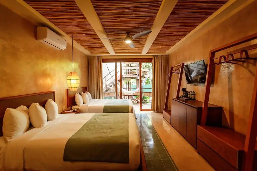 Geräumiges Hotelzimmer mit zwei Betten, TV und Balkontür ins Freie.