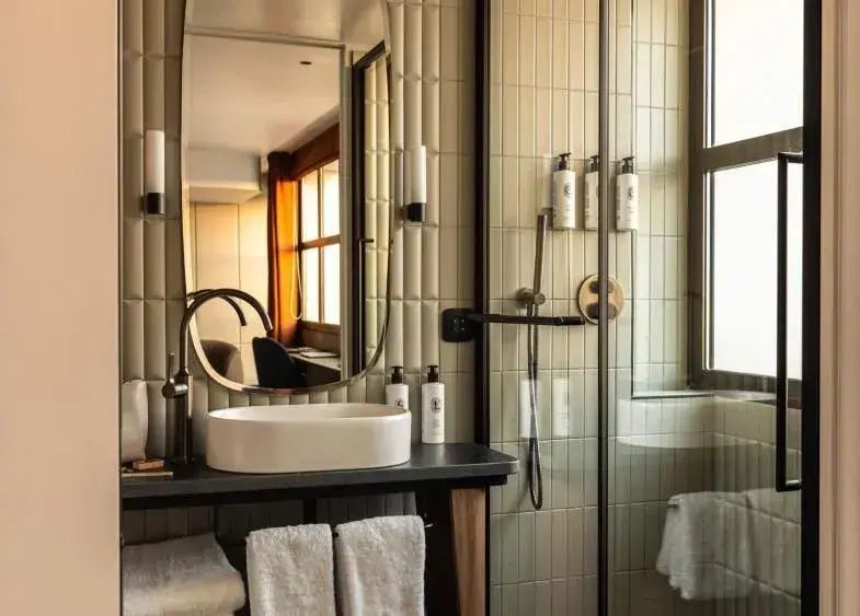 Moderner Waschtisch mit ovalem Waschbecken, ovalem Spiegel und angrenzender Glasdusche.