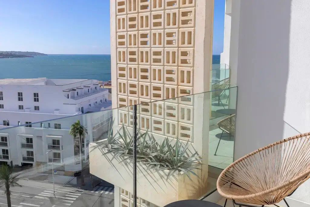 Balkon mit Glasgeländer und Blick auf die umliegenden Gebäude sowie das blaue Meer.