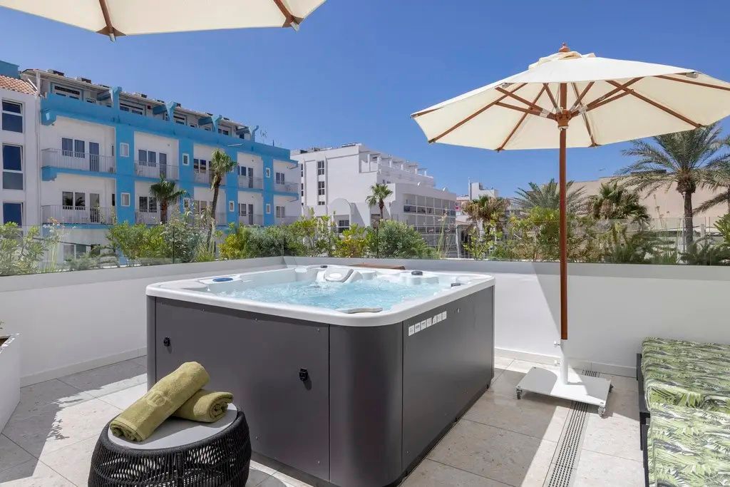 Whirlpool auf einer Dachterrasse mit aufgespanntem Sonnenschirm und Handtüchern.