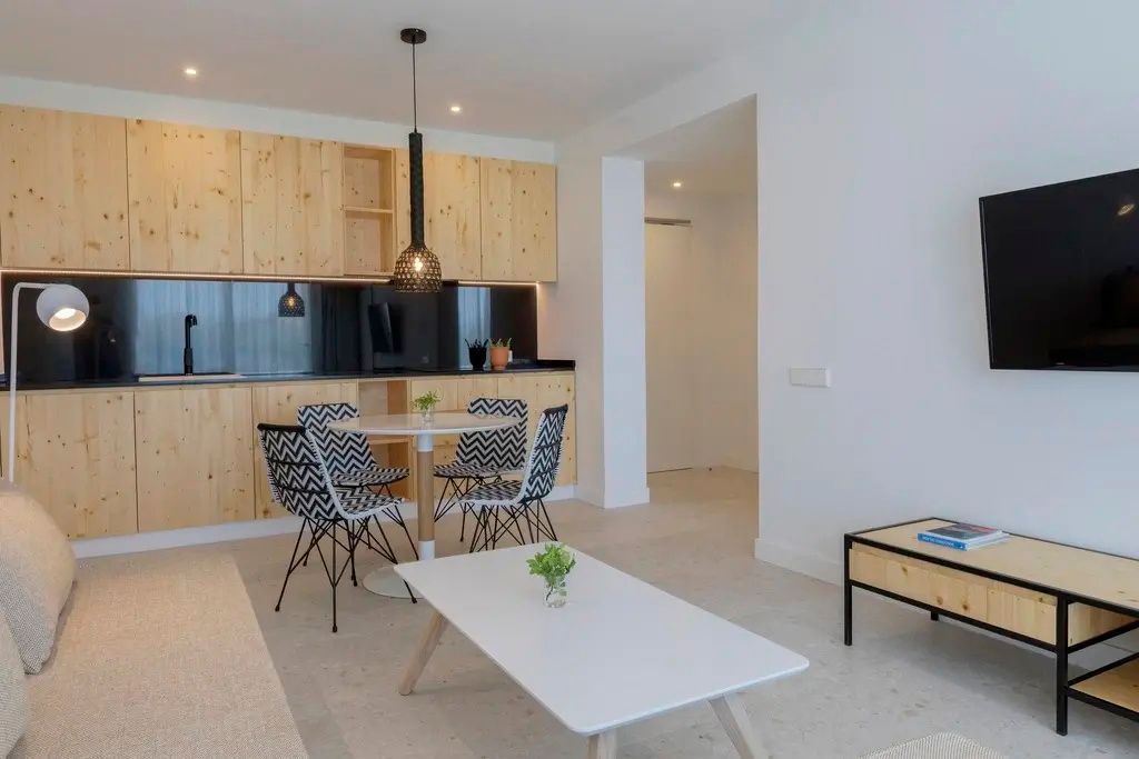 Wohnbereich einer Suite mit Küchenzeile aus Holz, Esstisch und Stühlen mit Muster.