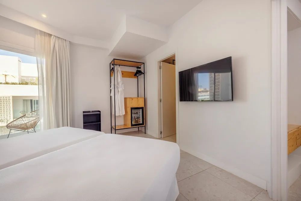 Hotelzimmer mit Doppelbett, Fernseher und einem offenen Garderobenelement.