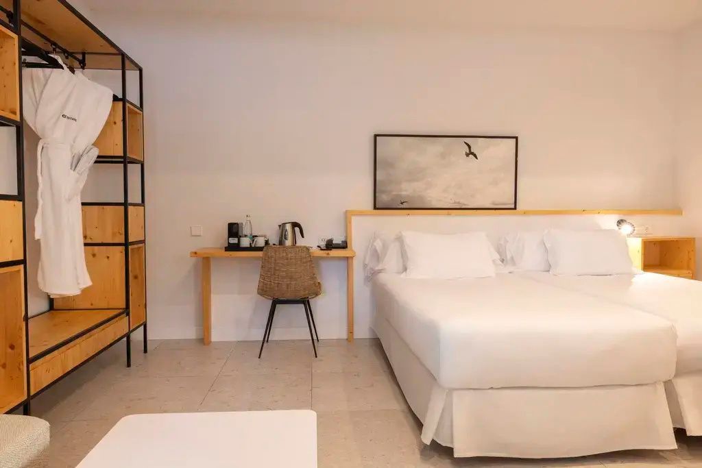 Schreibtisch mit Wasserkocher und Stuhl neben einem Doppelbett im Hotelzimmer.