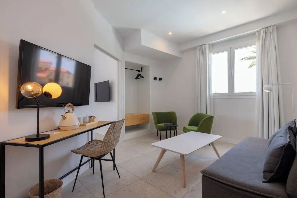 Wohnbereich einer Suite mit Schreibtisch, zwei grünen Sesseln und Couchtisch.