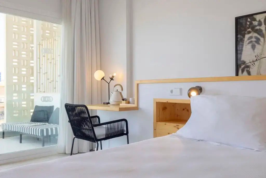 Schreibtischecke im Hotelzimmer mit schwarzem Stuhl, Lampe und Wasserkocher.