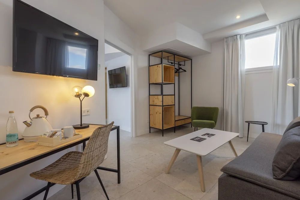Wohnbereich eines Hotelzimmers mit Schreibtisch, Couchtisch und offenem Regal.