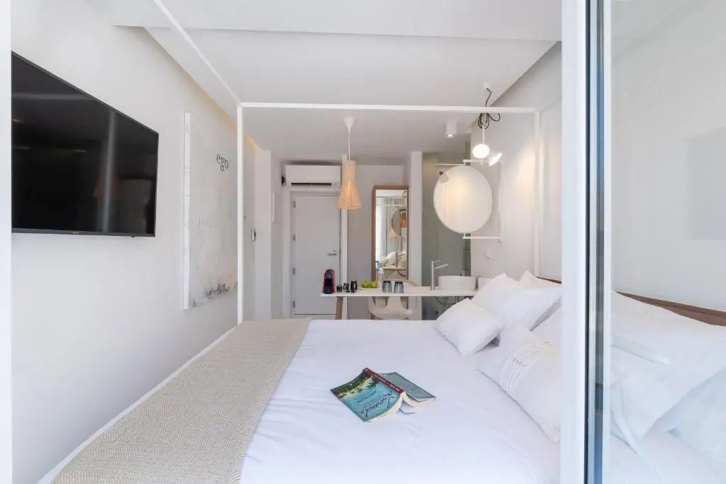 Modernes Hotelzimmer mit einem weißen Himmelbett, weißer Bettwäsche und offener Raumgestaltung.