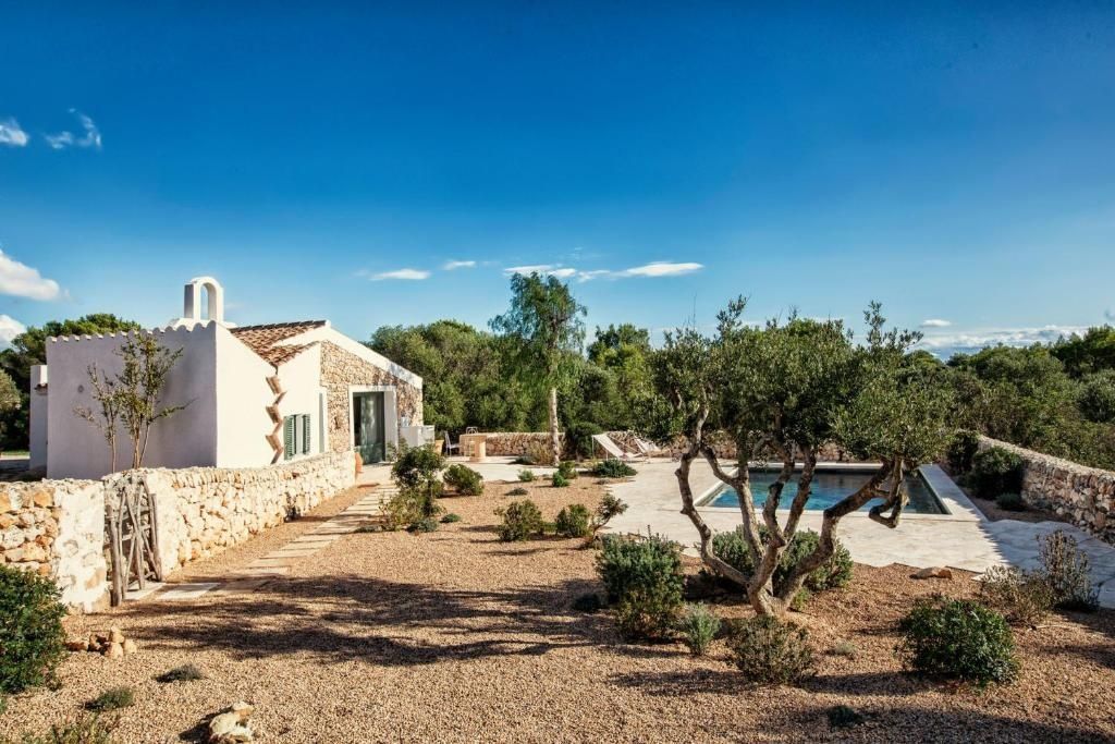 Mediterrane Außenanlage mit Natursteingebäude, Olivenbäumen und kleiner Poolanlage.