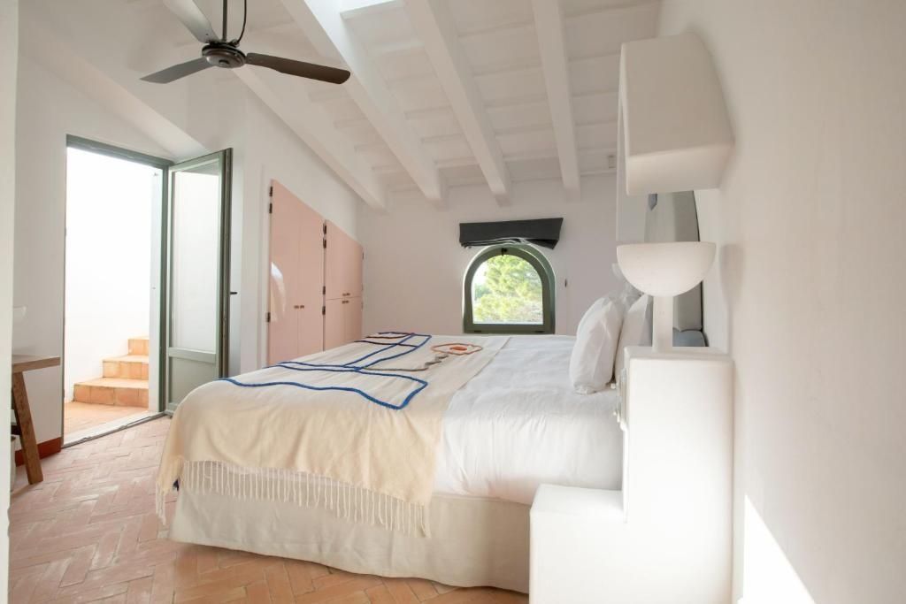 Schlafzimmer mit weißer Balkendecke, großem Doppelbett und rosa Schranktüren.