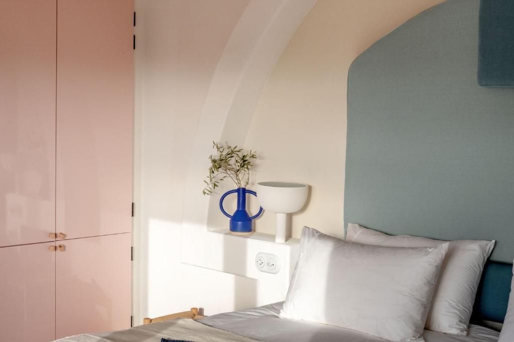 Helles Schlafzimmer mit einer blauen Vase in der Wandnische und einem gepolsterten Kopfteil.