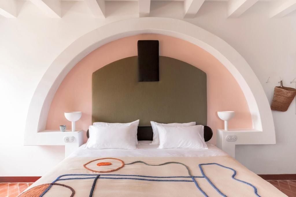 Doppelbett mit modernem Kopfteil in einer Rundbogennische mit rosa Wandgestaltung