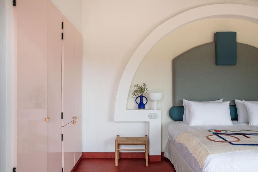 Schlafbereich mit rosa Kleiderschrank, weißem Bogenelement und Bett im Hotelzimmer