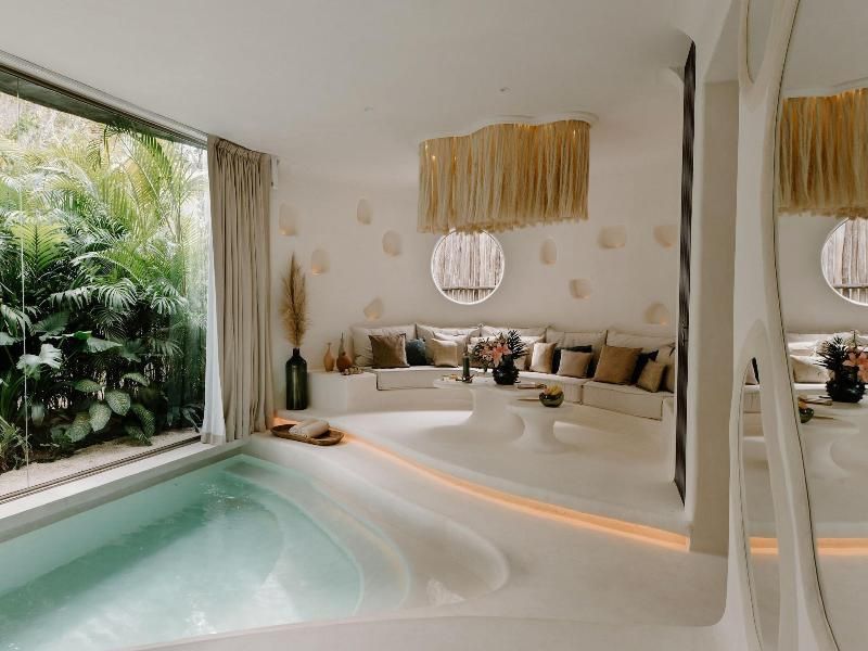 Sitzbereich einer Suite mit hellem Ecksofa, Tischen und direktem Zugang zum privaten Pool.