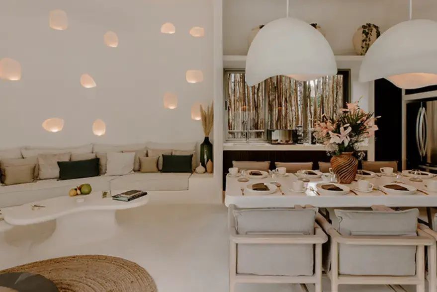 Heller Wohnbereich mit weiss eingebautem Sofa, Esstisch und runden Wandleuchten.