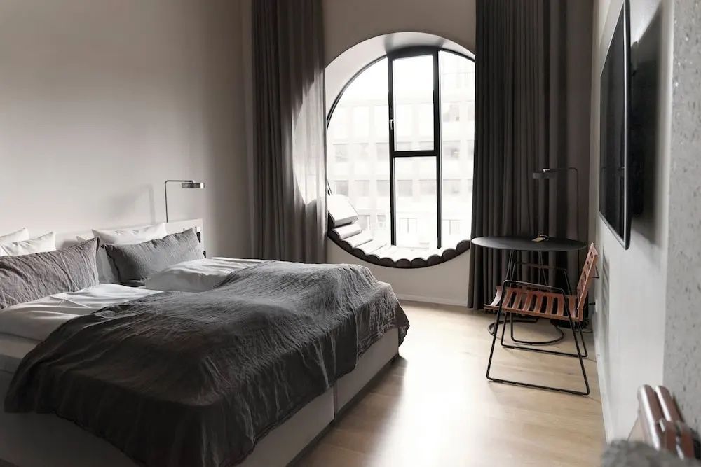 Hotelzimmer mit Doppelbett und einem großen runden Fenster mit integrierter Sitzfläche.