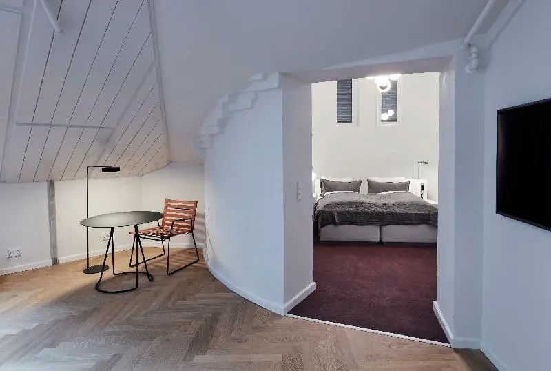 Blick durch einen Durchgang in das Schlafzimmer mit Doppelbett und angrenzender Sitzecke.