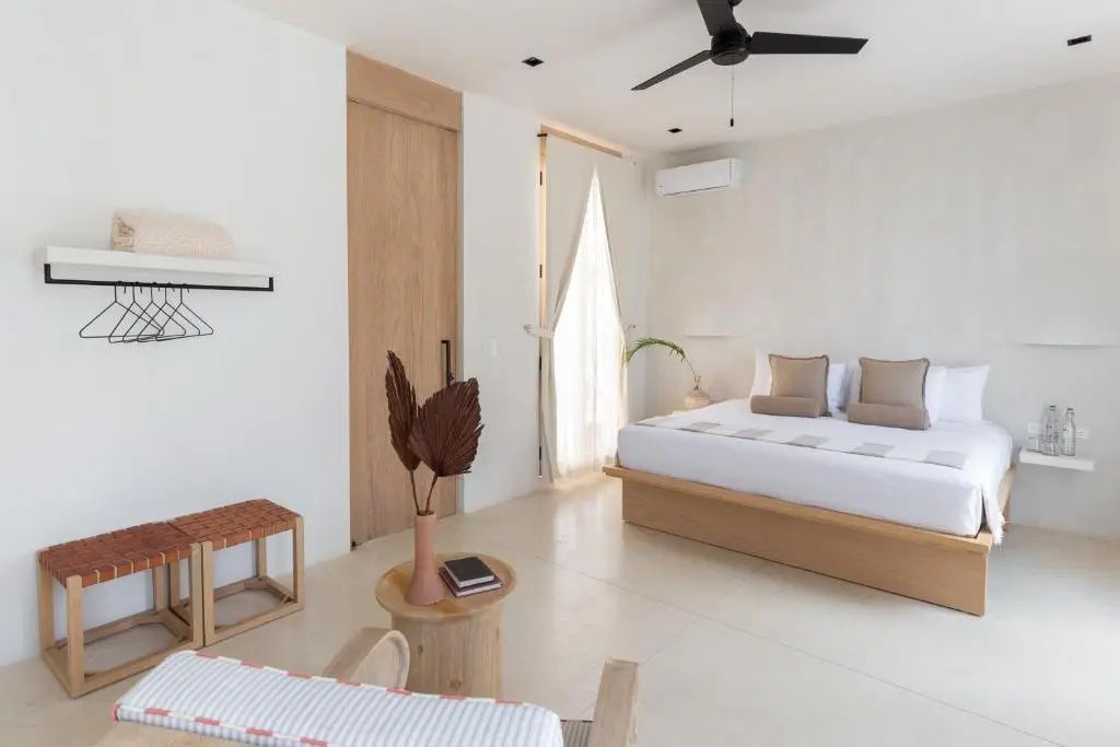 Schlafzimmer mit Doppelbett, Holzschiebetür, Deckenventilator und Holzmöbeln.