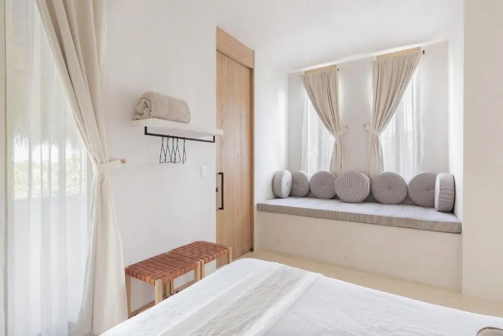 Eingebaute Sitzbank mit runden Kissen an den Fenstern im Hotelzimmer.