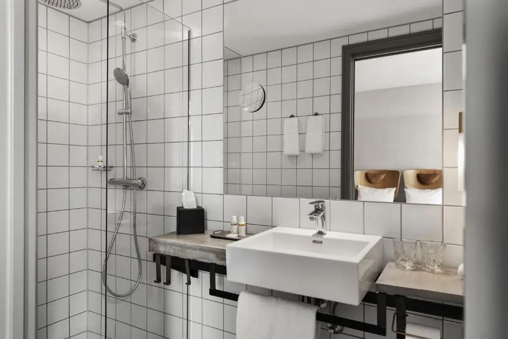 Badezimmer mit weiß gefliesten Wänden, Dusche und rechteckigem Waschbecken