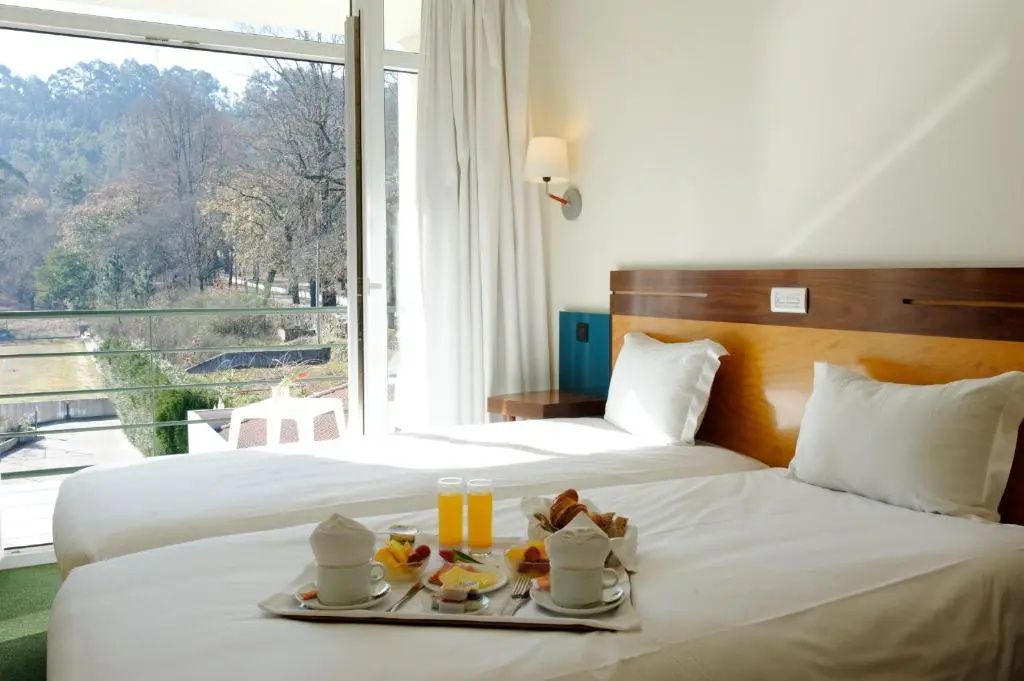 Doppelbett mit Frühstückstablett vor einem hellen Balkonfenster