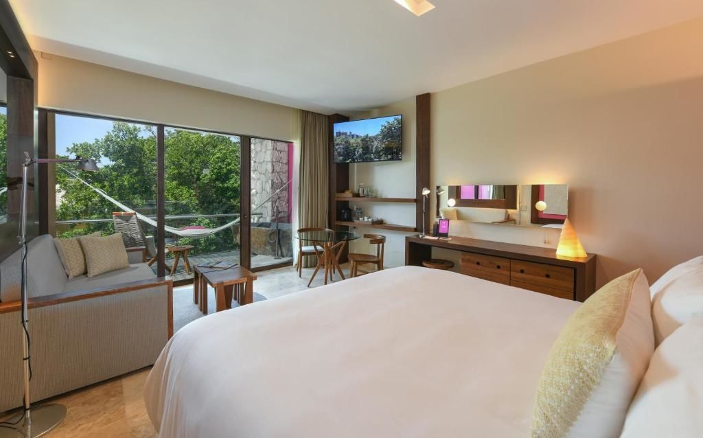 Doppelzimmer mit großem Bett, Fernseher an der Wand und Zugang zum Balkon mit Hängematte.