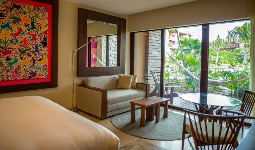 Sitzecke im Hotelzimmer mit kleinem Couchbereich, Holztisch und Fenster zur Terrasse.